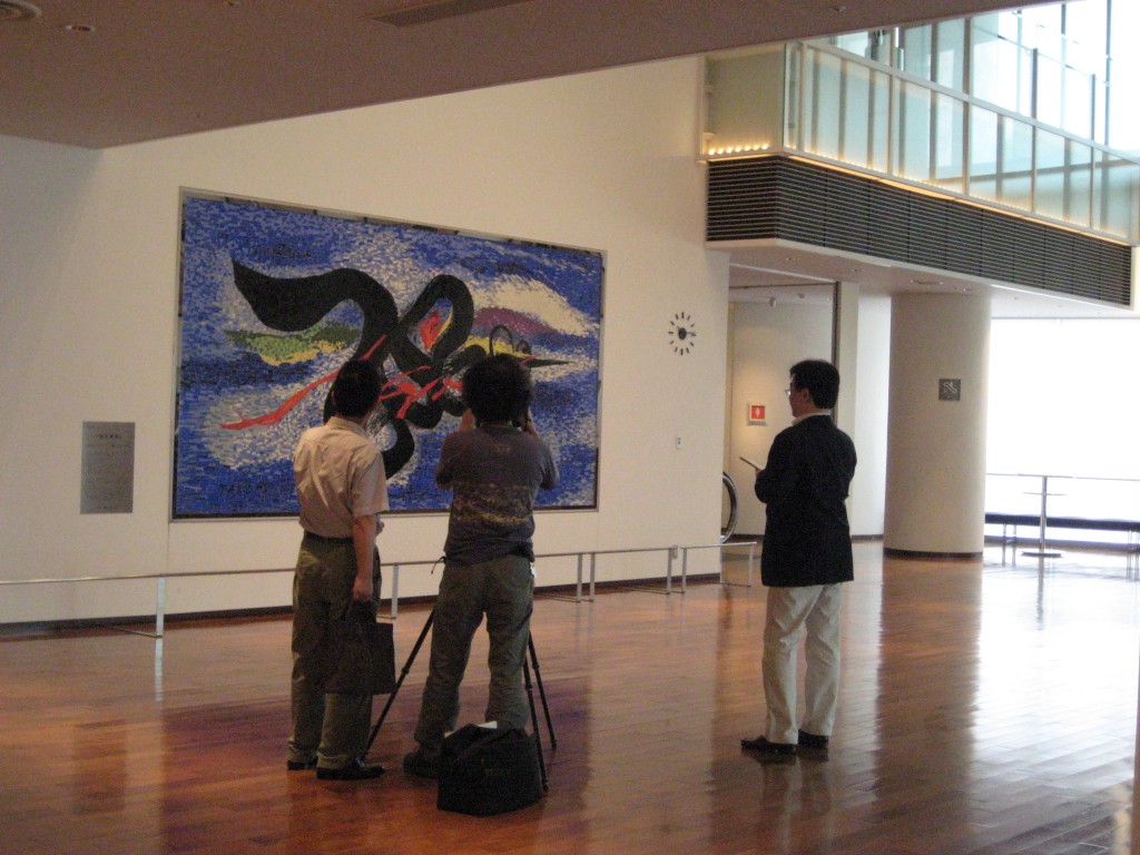 岡本太郎の展示前。3人の人が写っている。