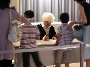 ホールクローク前で行われているホリヤンのサイン会の様子。髪の毛が真っ白。こどもにサインを書いている。