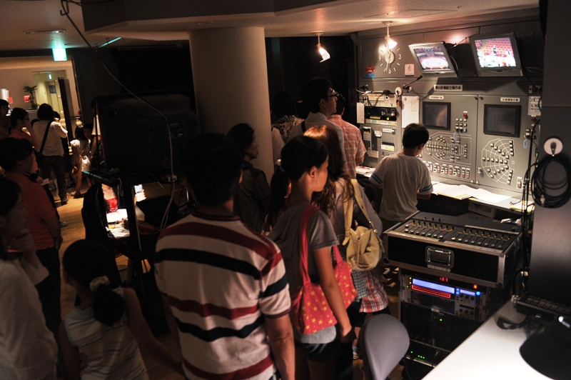 舞台下手袖にある操作盤を子どもたちが見学している写真。