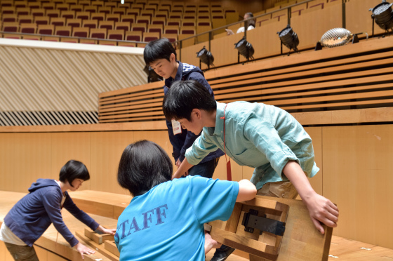 〔写真〕お仕事体験で合唱台を組む中学生たち