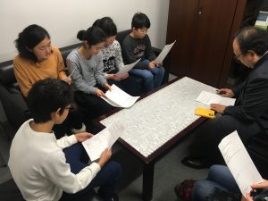 【写真】プレゼンを行っている様子。部長を囲んで、作った企画書を見ながら説明を行いました。