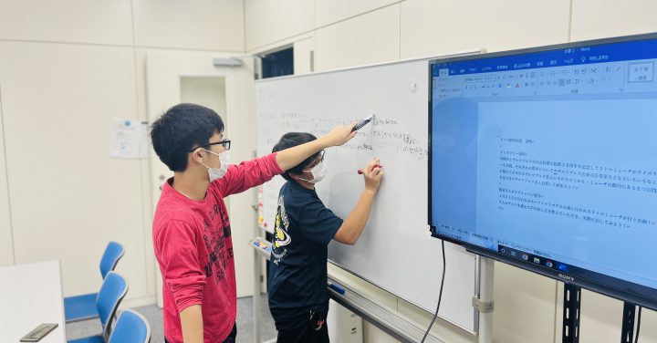 リトルミューザ会議中の様子。ホワイトボードにアイディアを書き込む2人のメンバー。