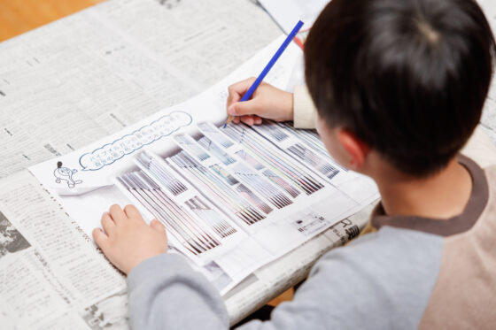新聞紙が敷かれた机の上でパイプオルガンに色鉛筆で1本ずつカラフルに色をつけている。