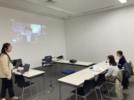 会場スクリーンに映し出されるリモート参加の飯田氏、席について自己紹介する参加者、アテンドするミューザスタッフ。