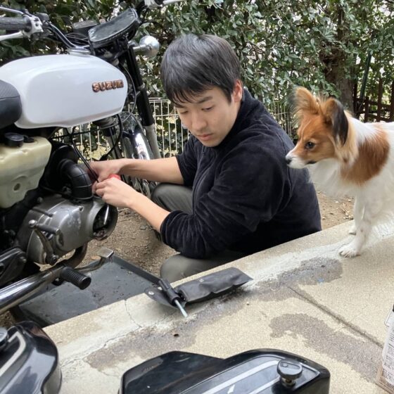 バイクをいじりながら愛犬と戯れる松本さん。