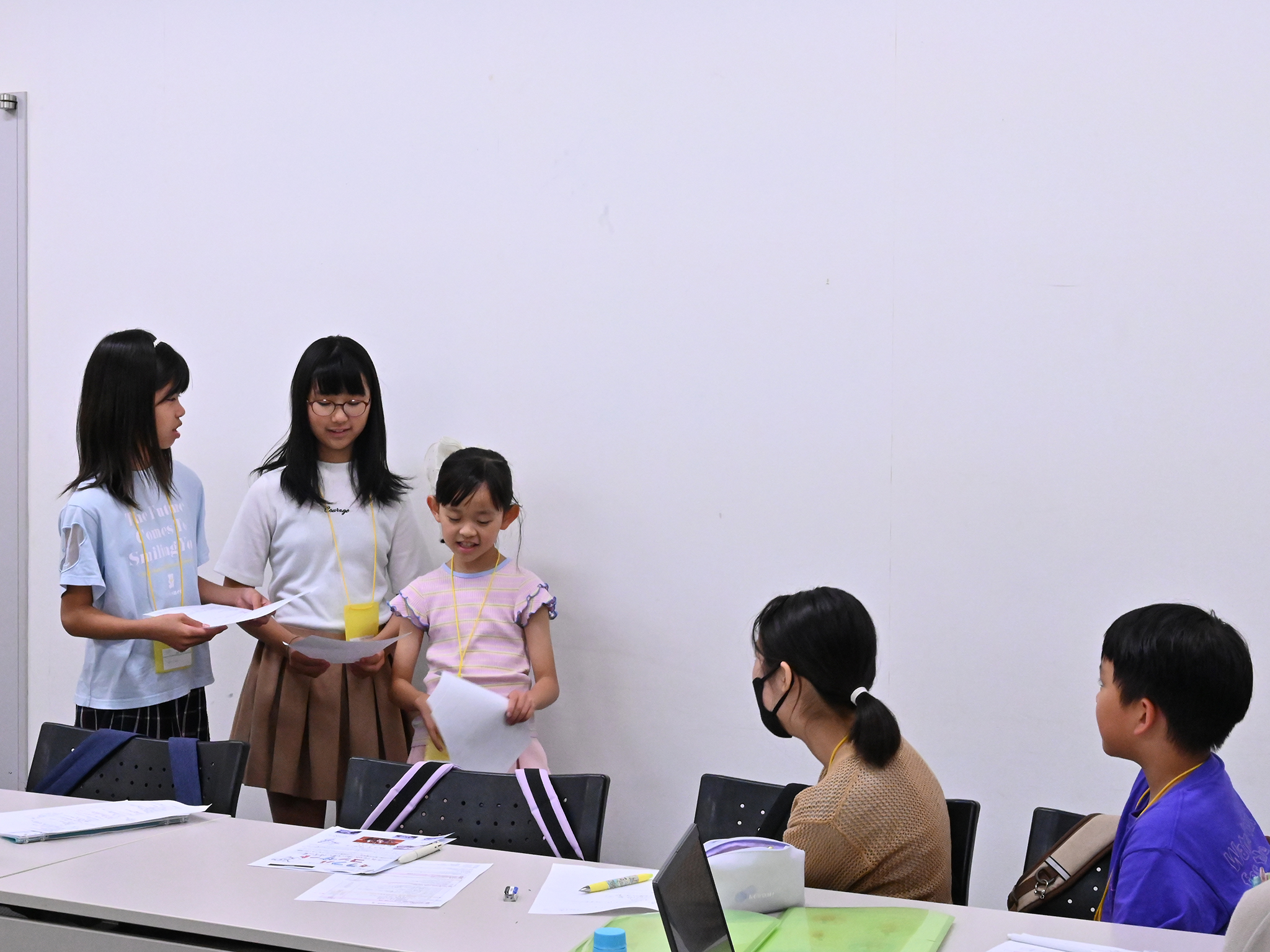 広報班の3人が、企画班の2人の元へ来ている写真。横にいる広報班の方に体を向けて座る企画班メンバー。