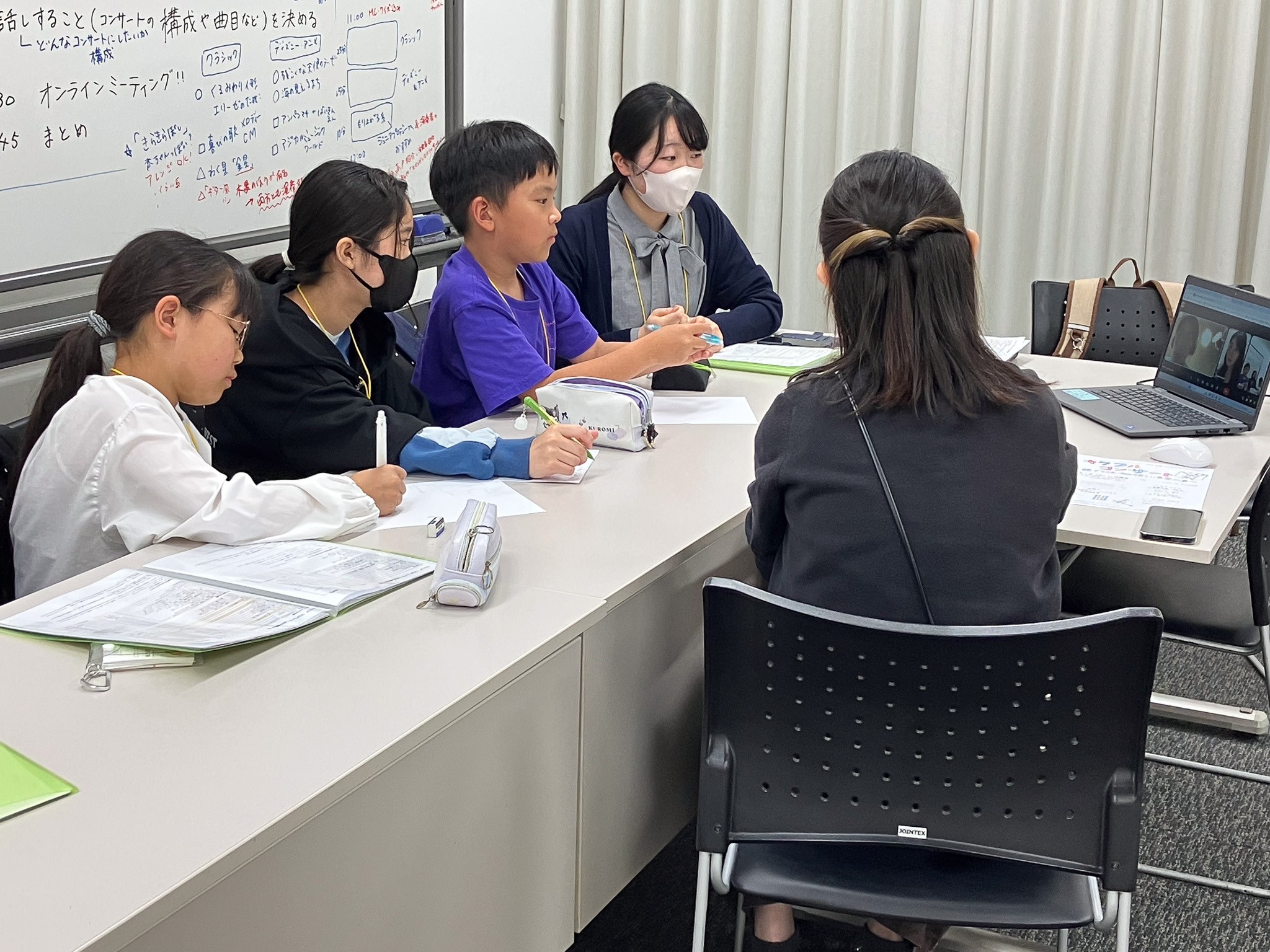 横一列に3名と大人スタッフが座り、パソコンを見ている写真。パソコン画面の中には、土屋さんと多井さん。横には東京交響楽団の榎さんが座っている後ろ姿。