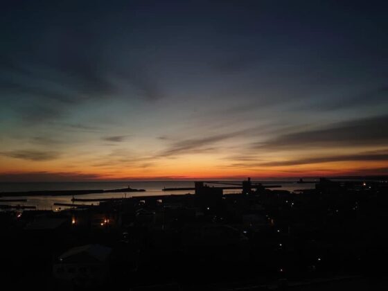 オホーツク海から太陽が昇るところ。濃い紺色の空の中、水平線の際がオレンジ色にそまっている。