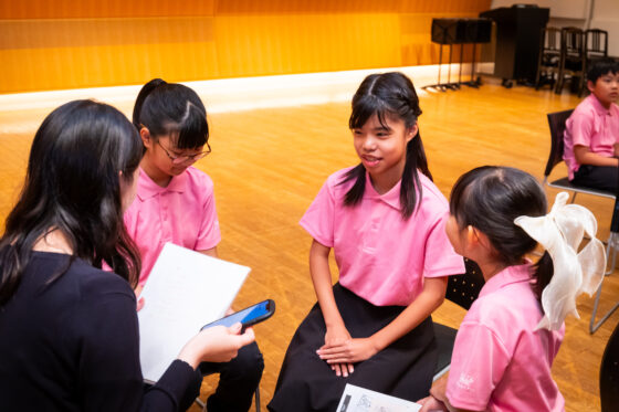 広報班3名と記者1名が膝を突き合わせて座っている写真。1人のメンバーが記者の方を見て話している