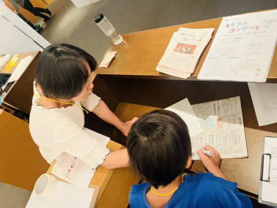 机上に新聞紙を引いて、その上で何かを書いている運営班メンバーの写真