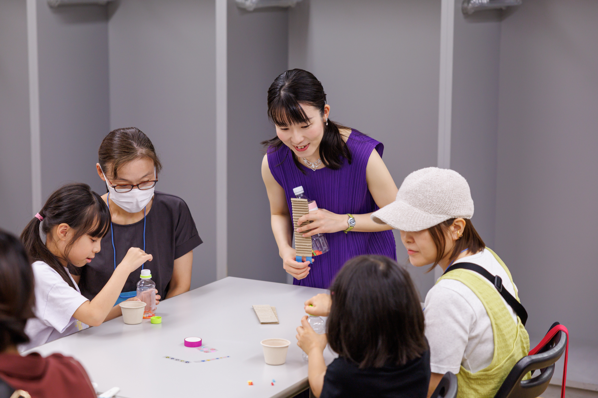 ペットボトルの中に細かく切ったストローを入れている参加者。講師の樋口さんが横から笑顔で見守っている。