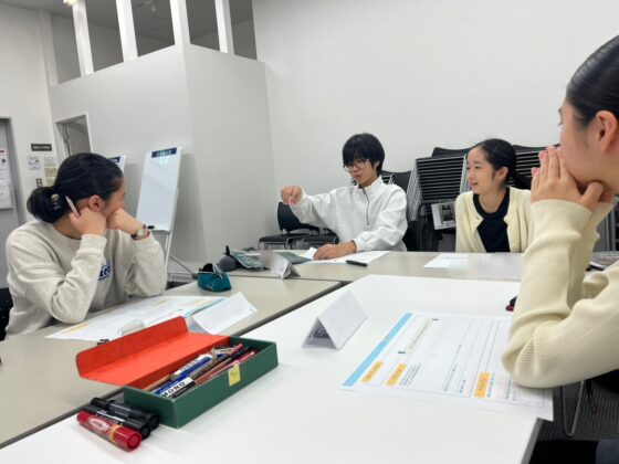 グループディスカッション風景。中央のメンバーが発言しており、他の3人は熱心に耳を傾けたり、笑顔で反応したりしている。