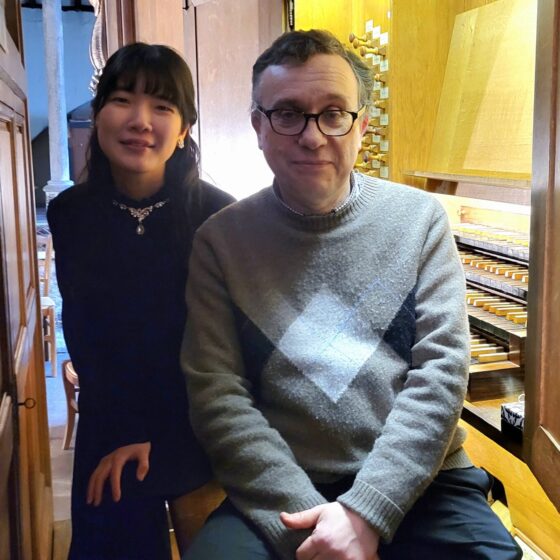 澤さん(左)とフランソワさん(右)がパイプオルガンのベンチに座っている。