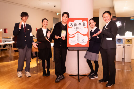 川瀬さんとリトルミューザ4人が「名曲全集」の大入り袋の掲示物を囲んで笑顔で並んでいる集合写真