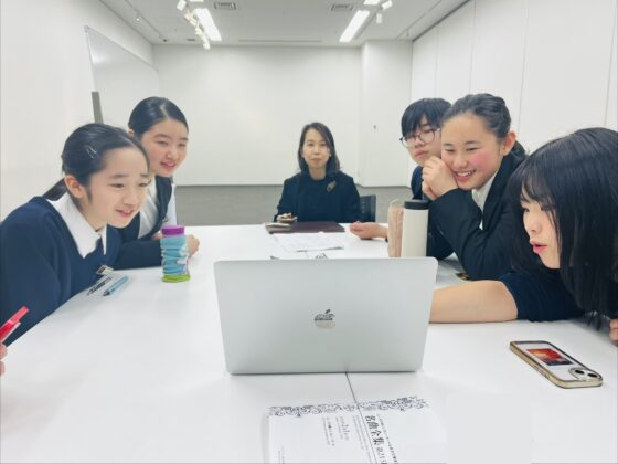 机上に置かれたパソコン画面を覗き込むメンバーたちの写真。みんな前のめりで口角が上がり嬉しそうな表情をしている